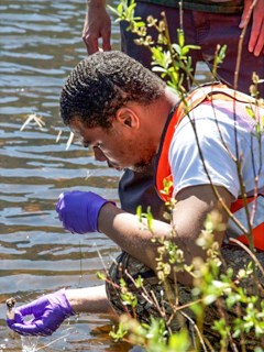 CDRLC Youth A young man lifts water sampling equipment from a river.