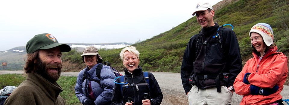 a ranger laughs with 4 visitors on a hike a ranger laughs with 4 visitors on a hike