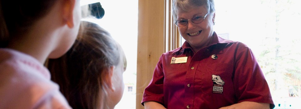 A woman smiles down at children A woman smiles down at children