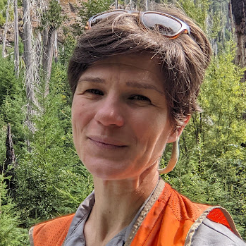 Headshot of Beth Fallon, a smiling white woman with short dark hair wearing a reflective safety vest.