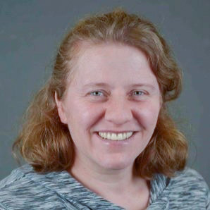 Headshot of Katherine Hegewisch, a smiling white woman with wavy red hair.