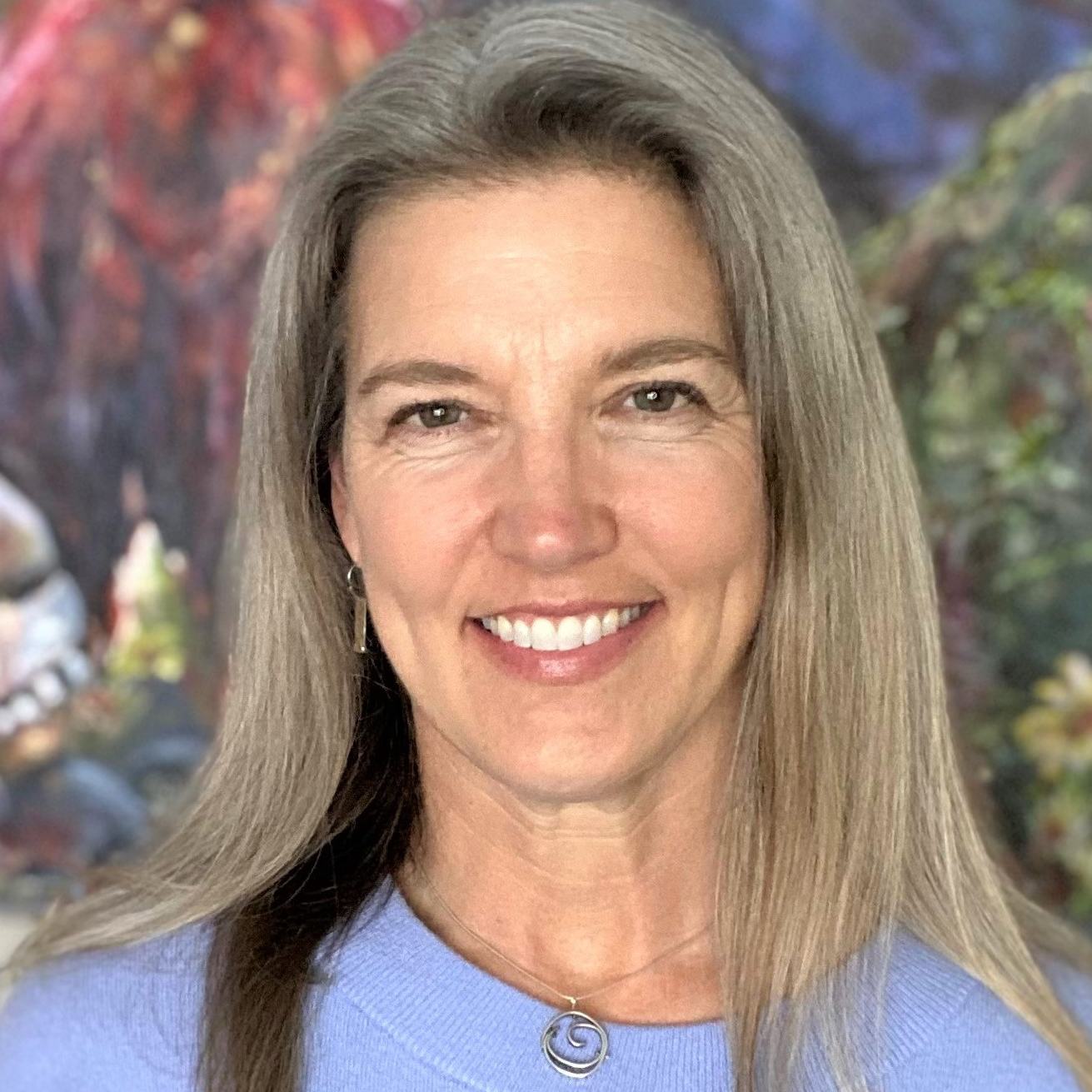 Headshot of Andrea Lyons, a smiling white woman with long grey hair.