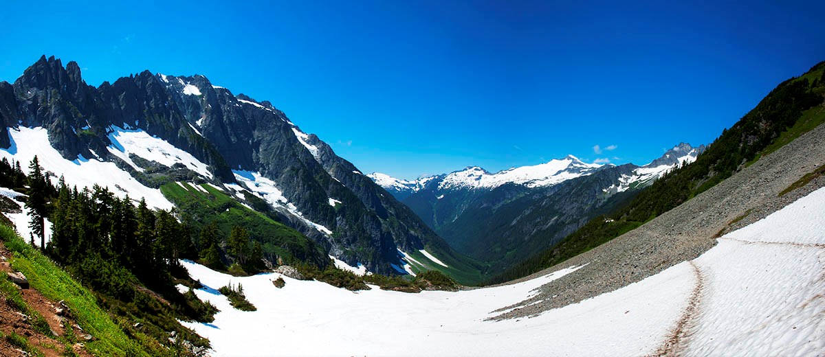 Looking down a glacial valley at mountains in the distance on a clear day