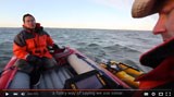 Still-frame of a video; two people sit in a boat on the water.