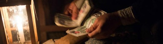 A park staff member counts money during an historic reenactment