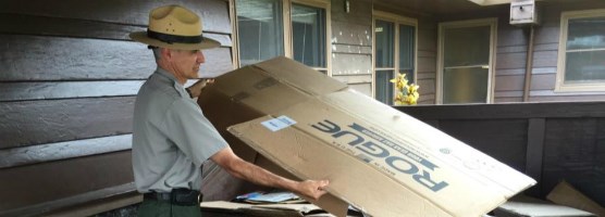 A park ranger puts a large piece of cardboard in the recycling bin at his park