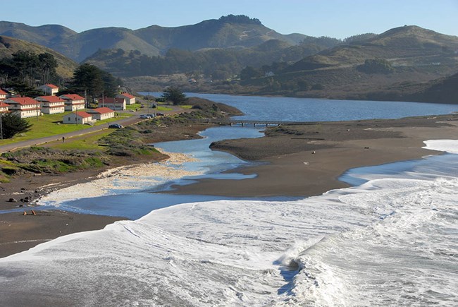 Waves washing over a beach and into a coastal lagoon