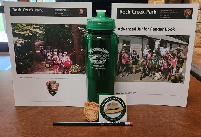 display of junior ranger items including booklets, a reusable water bottle, a pencil, and a sticker