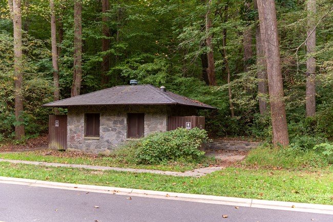 small gray and brown building nestled near the edge of the forest