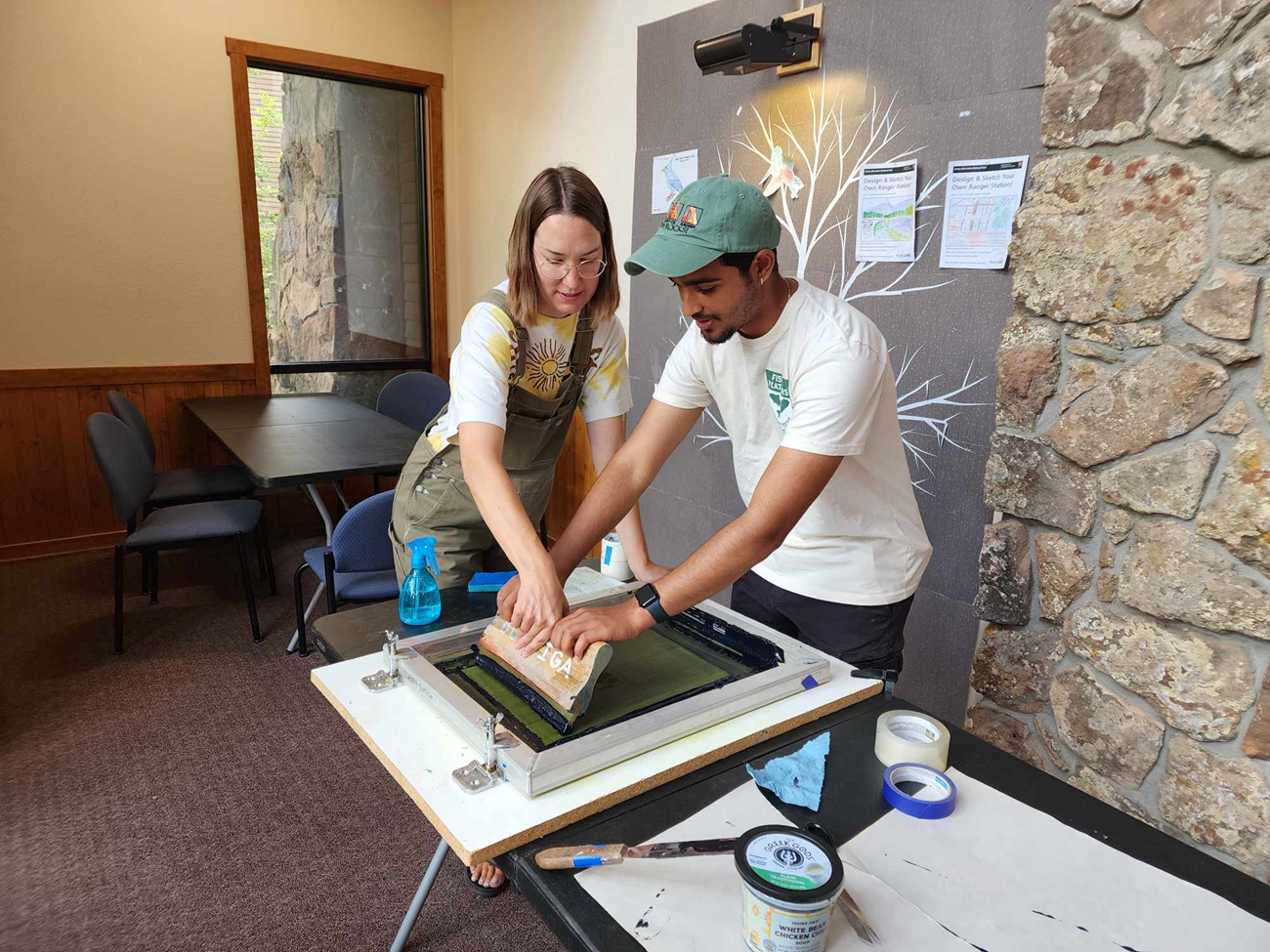 Claudia Borfiga helping a visitor with screenprinting at the Print A Card Program