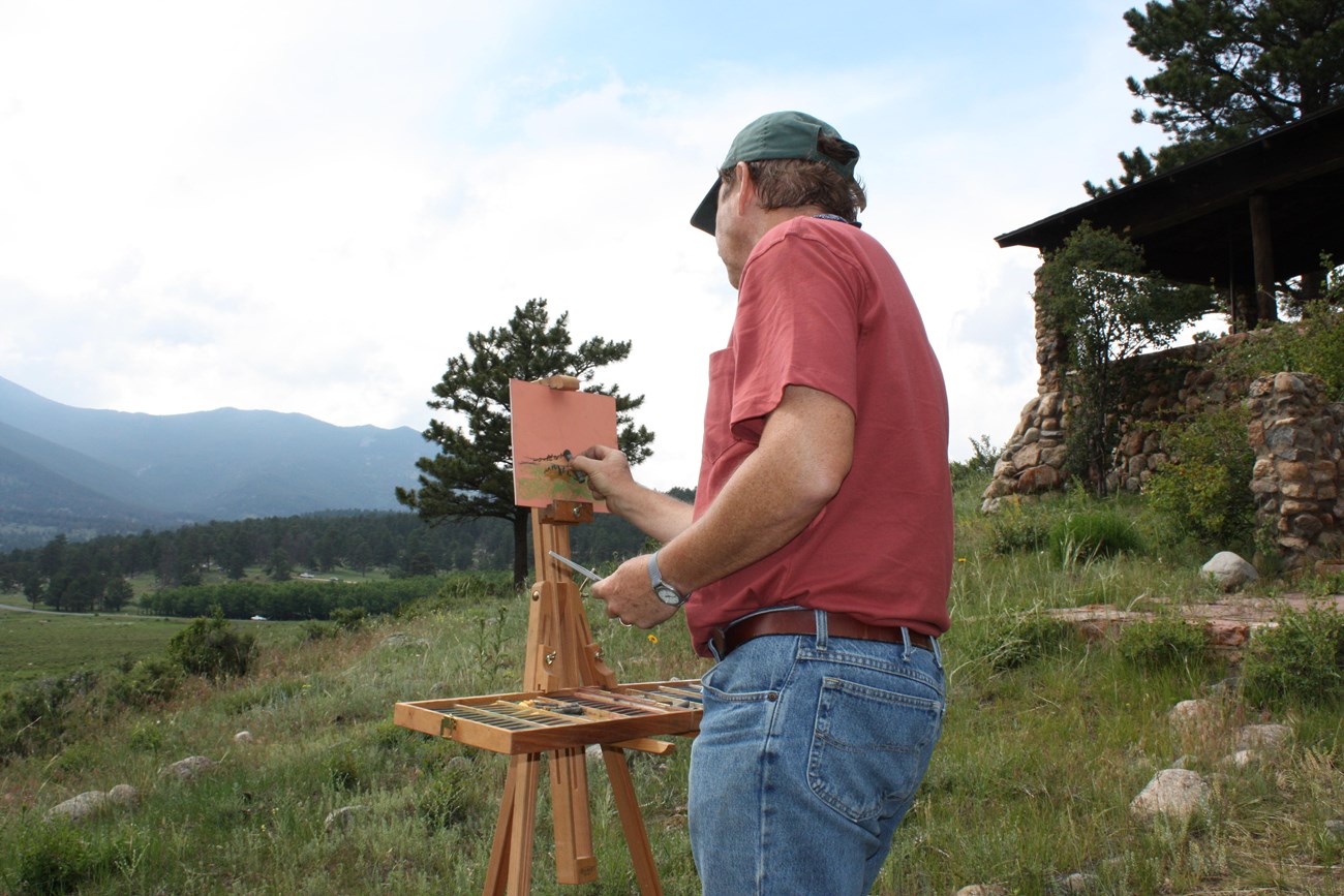 Artist-In-Residence John Hulsey is painting with a brush while looking at Moraine Park