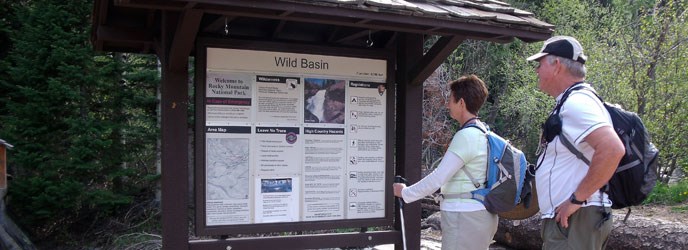 Visitors read the Wild Basin trailhead sign Visitors read the Wild Basin trailhead sign