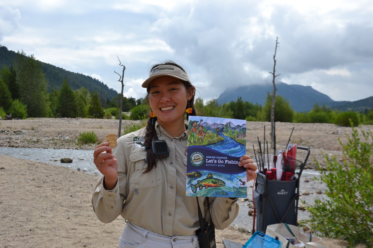 An intern is holding up a Junior Angler Book and Badge