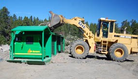 Photo park staff use a front loader to deposit beetle-killed trees into the park's air curtain burner.