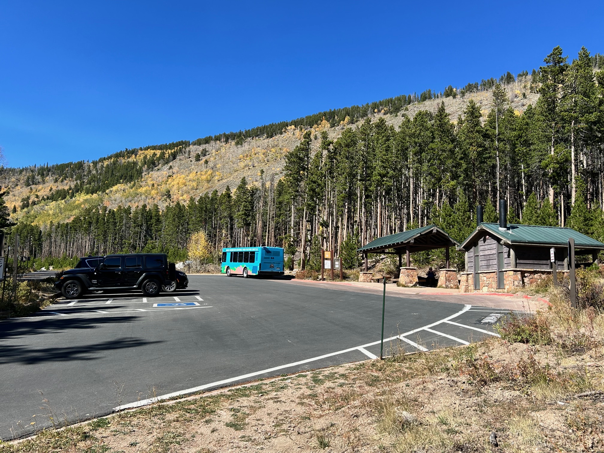 Bierstadt Shuttle Stop, parking area and Vault Toilet Vehicles parked in Bierstadt Lake Trailhead parking area with vault toilet building and shuttle stop.