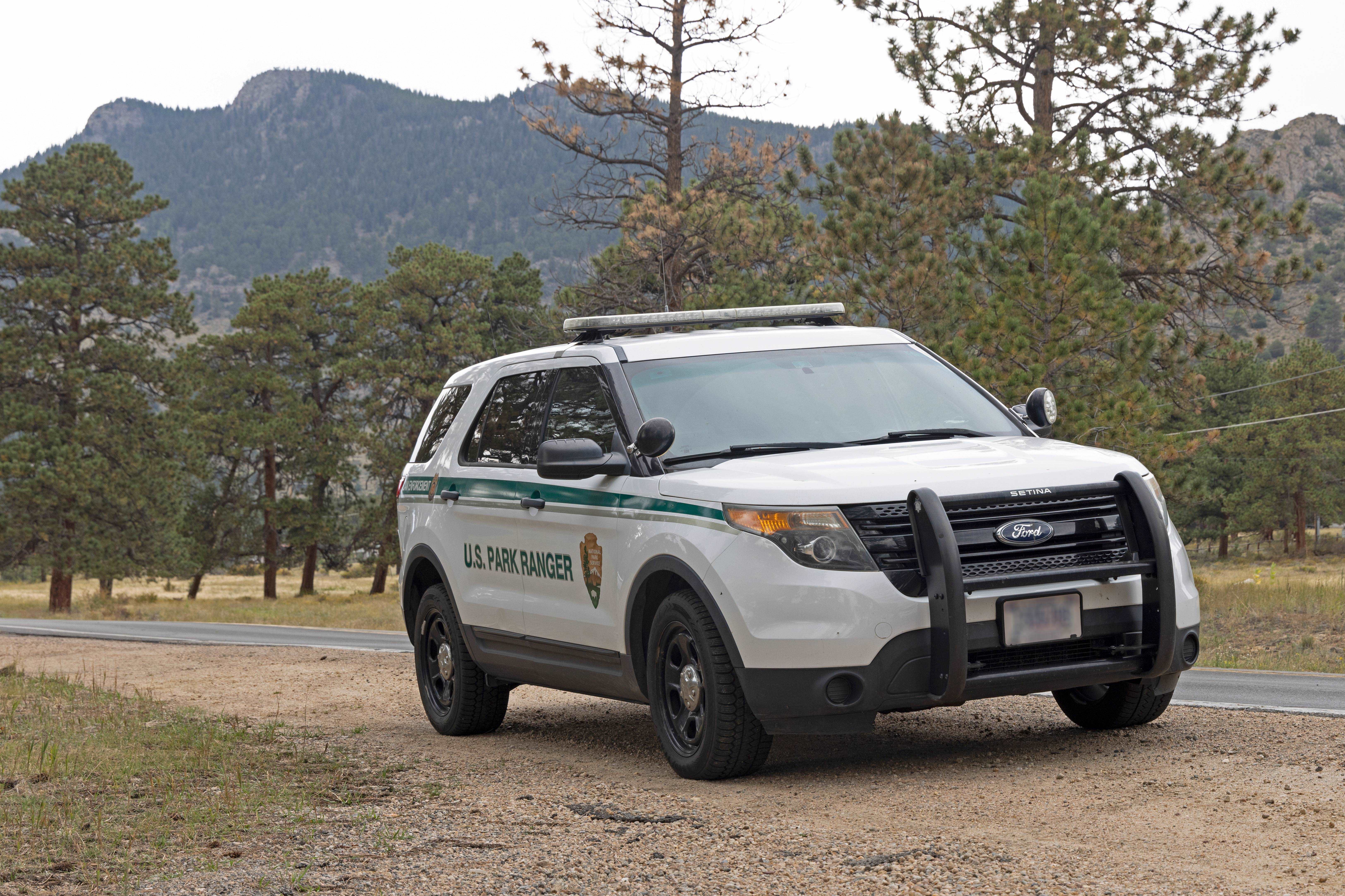 Courtesy RMNP_LE Vehicle with High Drive in background_crop_Reduced Size An NPS law enforcement vehicle is pulled over on the side of a road inside RMNP on a cloudy day