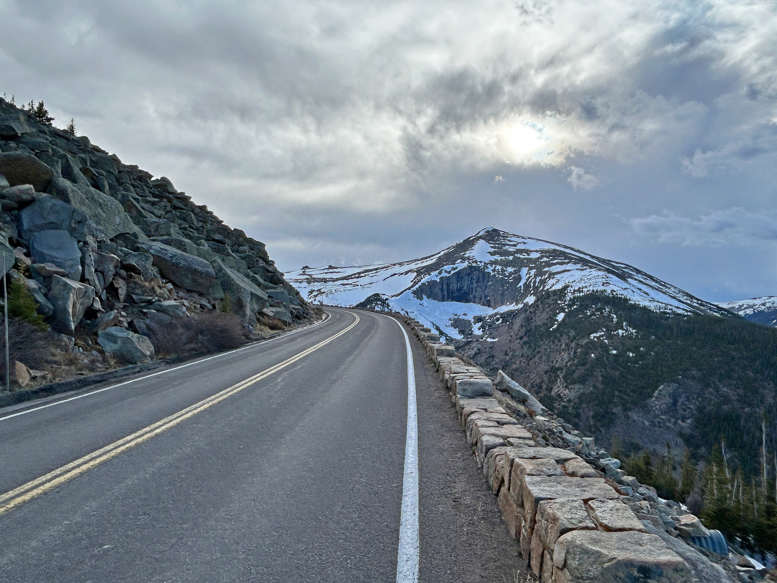 High elevation Trail Ridge Road with rocky summits and snow in the distance.