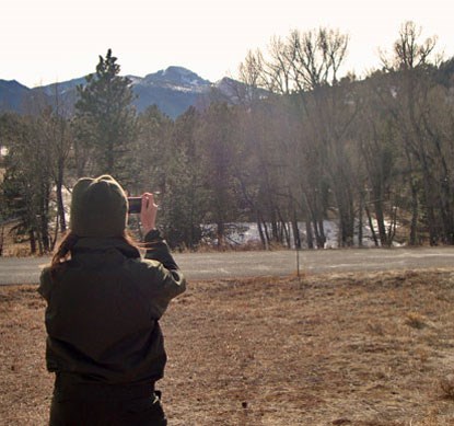 Ranger Chelsea taking a picture of Longs Peak.
