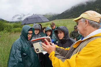 Students study a field guide to identify different bird species. Students study a field guide to identify different bird species.