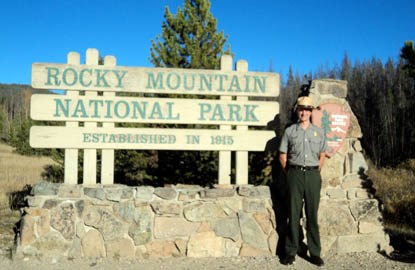 Photo Ranger Andrew standing in front of official Rocky Mountain National Park sign.