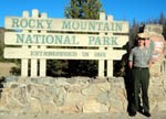 Photo ranger standing in front of park sign at west side entrance.