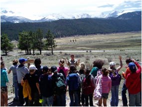 Photo of GeoCorps Environmental Education Intern with a group of students looking at the glacially carved landscape of Moraine Park