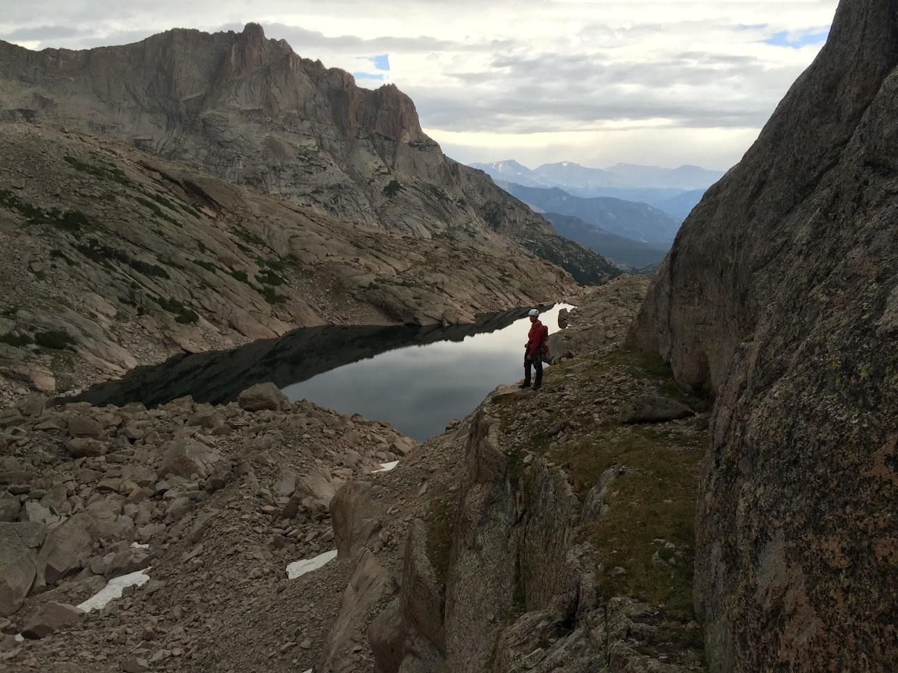 A climber is standing above Frozen Lake in Glacier Gorge