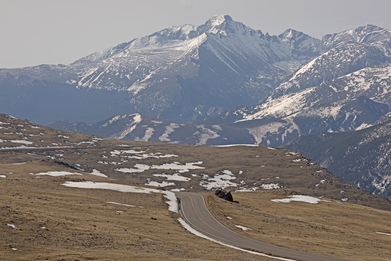 A section of Trail Ridge Road seen near Rock Cut, the road is clear of snow with patches of snow on tundra near the road.