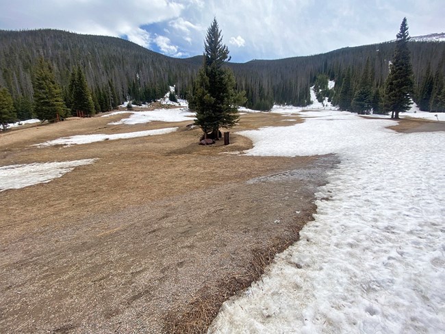 Hidden Valley Sledding Hill. Most of the snow has melted and bare ground is exposed. There are patches of snow, mostly on the right side of the hill.