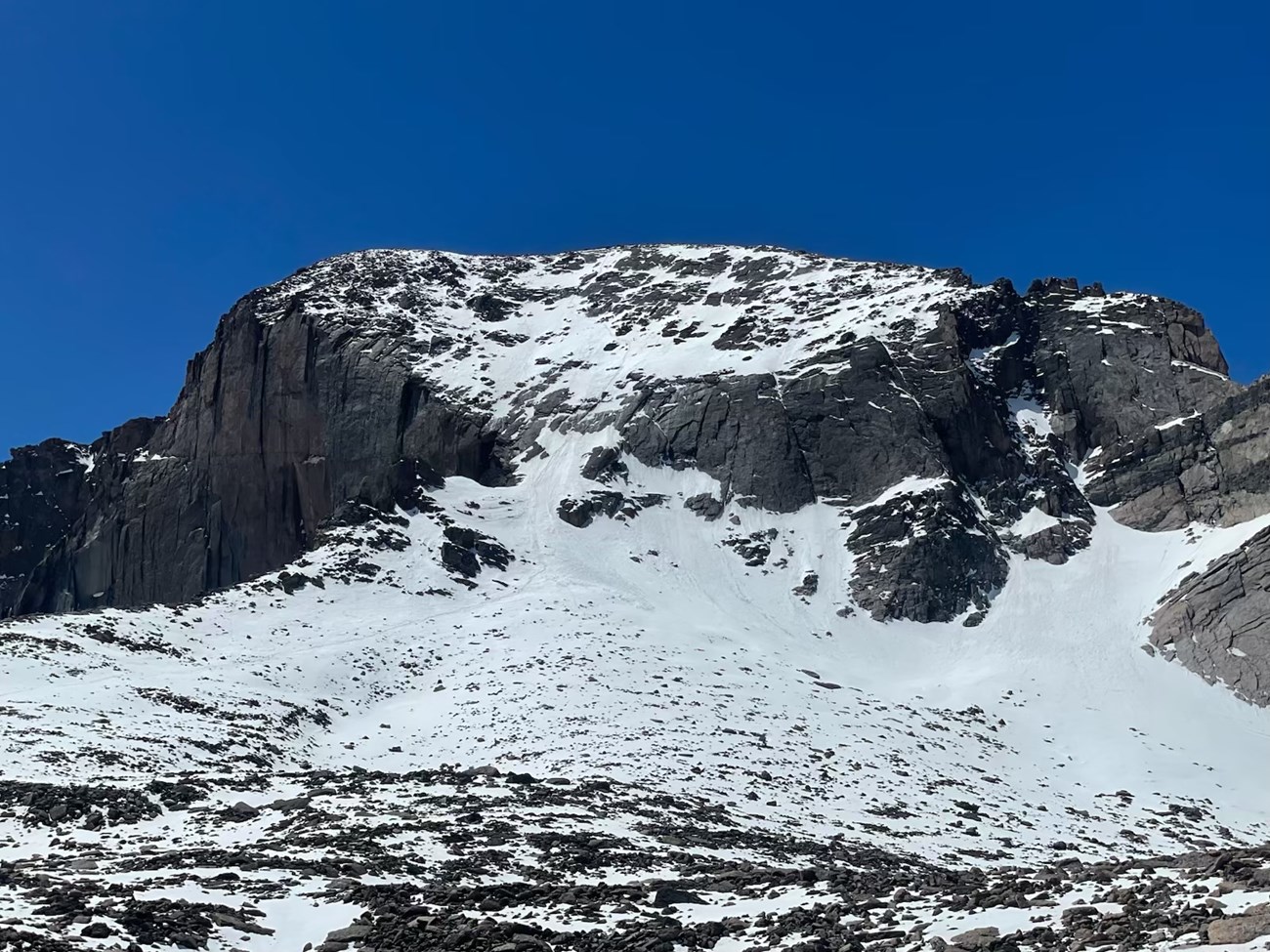 North Face of Longs Peak, covered with snow and ice on a sunny day with clear, blue sky above