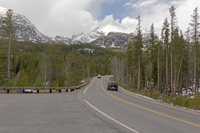 Two cars are driving on Bear Lake Road on a overcast and cloudy day. The road is dry.