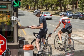 Photo of two bicyclist paying the park entrance fee at Fall River Entrance Station.