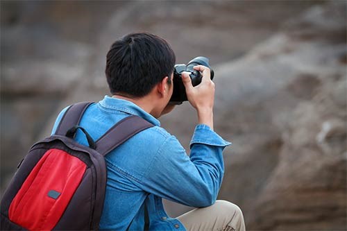 View from the back of a person holding a camera with his elbows on his knees for stabilization