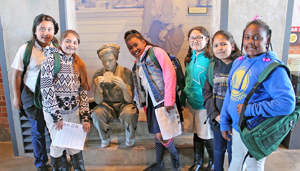 Young female students are posing with the "Rosie" statue.