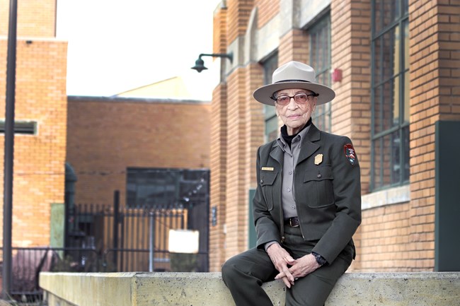 An older African American woman in a ranger uniform sits on a concrete slab.
