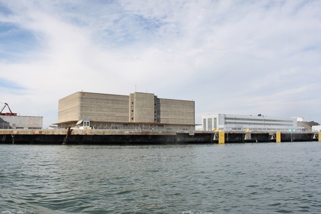 Large warehouse building sitting next to dock. Seen from boat.