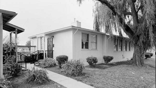 Historic photo of a one-story home in Nystrom Village. Trees and sidewalk seen.