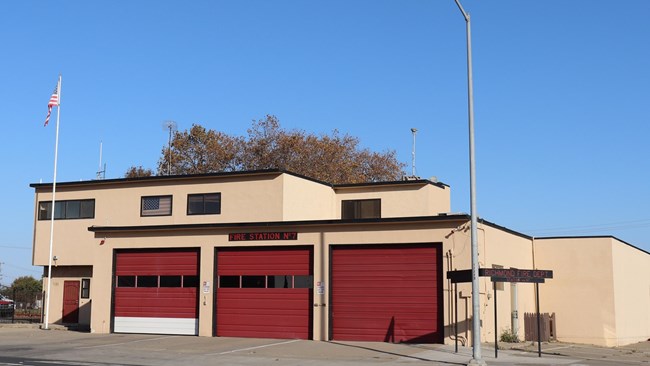 One story building with three garage doors. Flag out front.