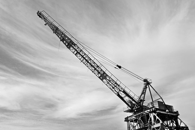 A large crane shown against the sky. Black and white photo.