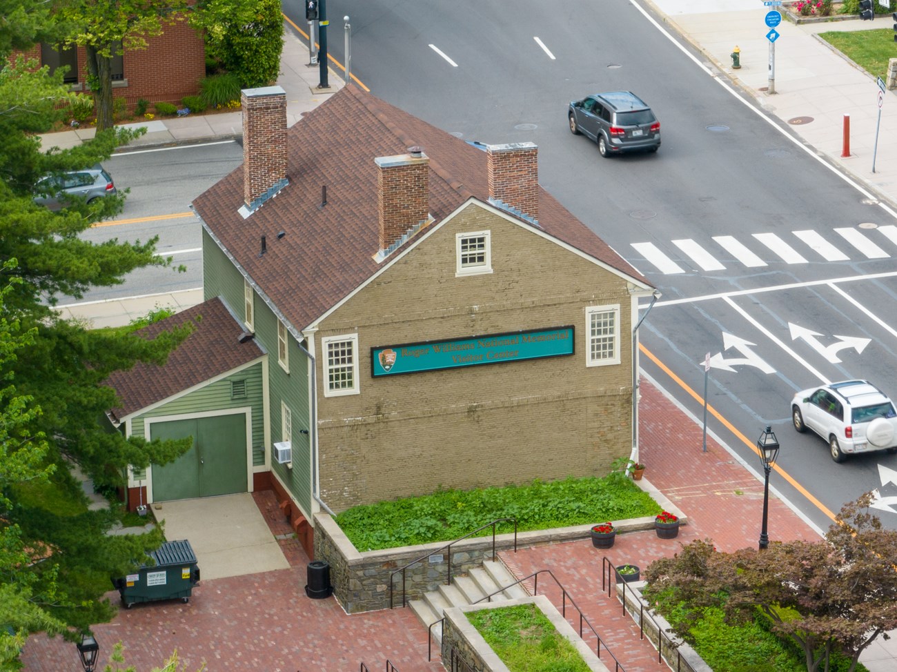 A green and tan historc building on a busy street