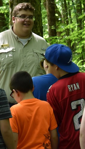 A volunteer leads school children on a tour to the cave shelter