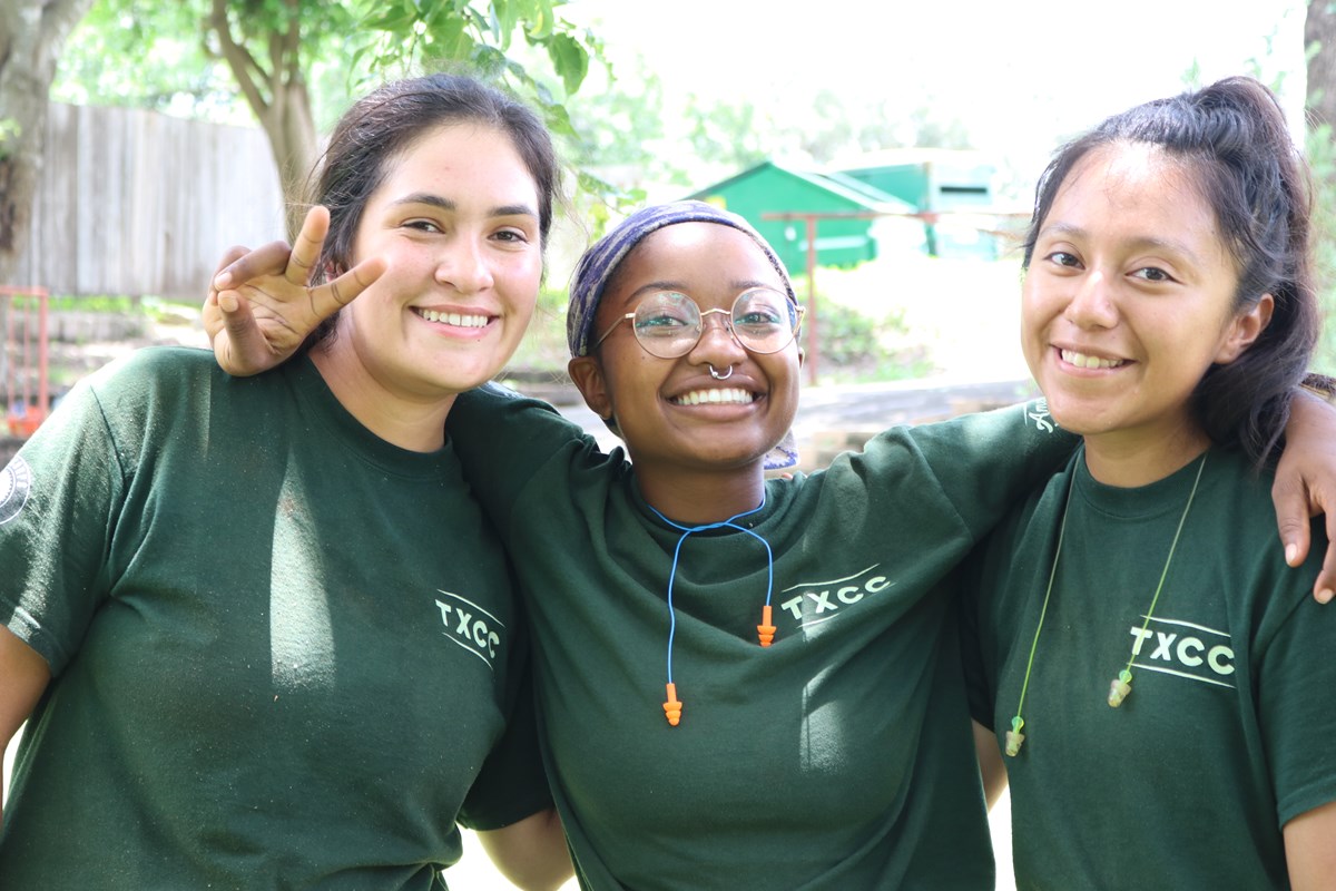 Three female young adult TXCC service members smile at the camera