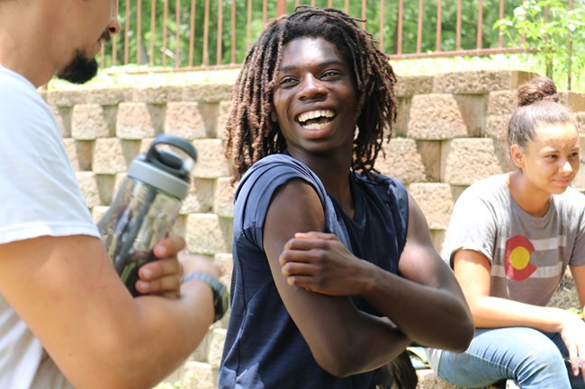 Young man in short sleeves smiles at another work crew member