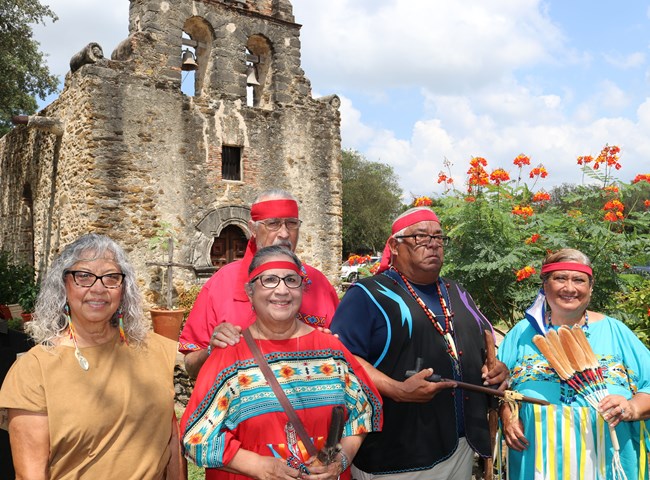 Group in traditional native clothing in front of Mission Espada.