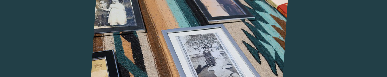 Wide image of framed portraits of mission descendants laying on a table.