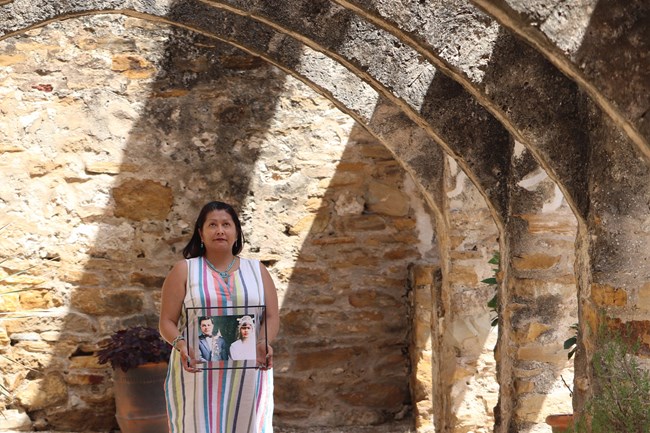 Woman standing under stone arches.