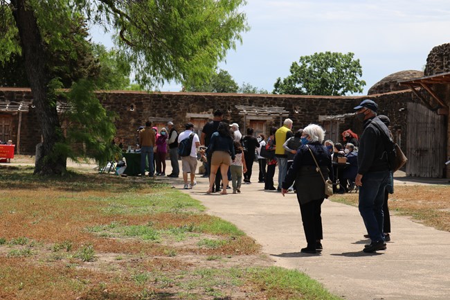 Groups of visitors walk down the paved path at Mission San Jose.