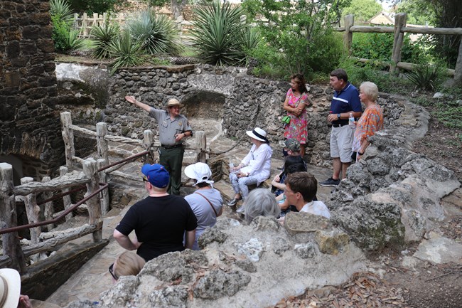 Park Ranger demonstrates historic grist mill for group of visitors outdoors