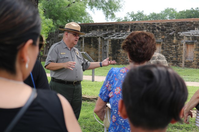 Male Park Ranger stands in front of group of visitors in Mission San Jose during a ranger led program