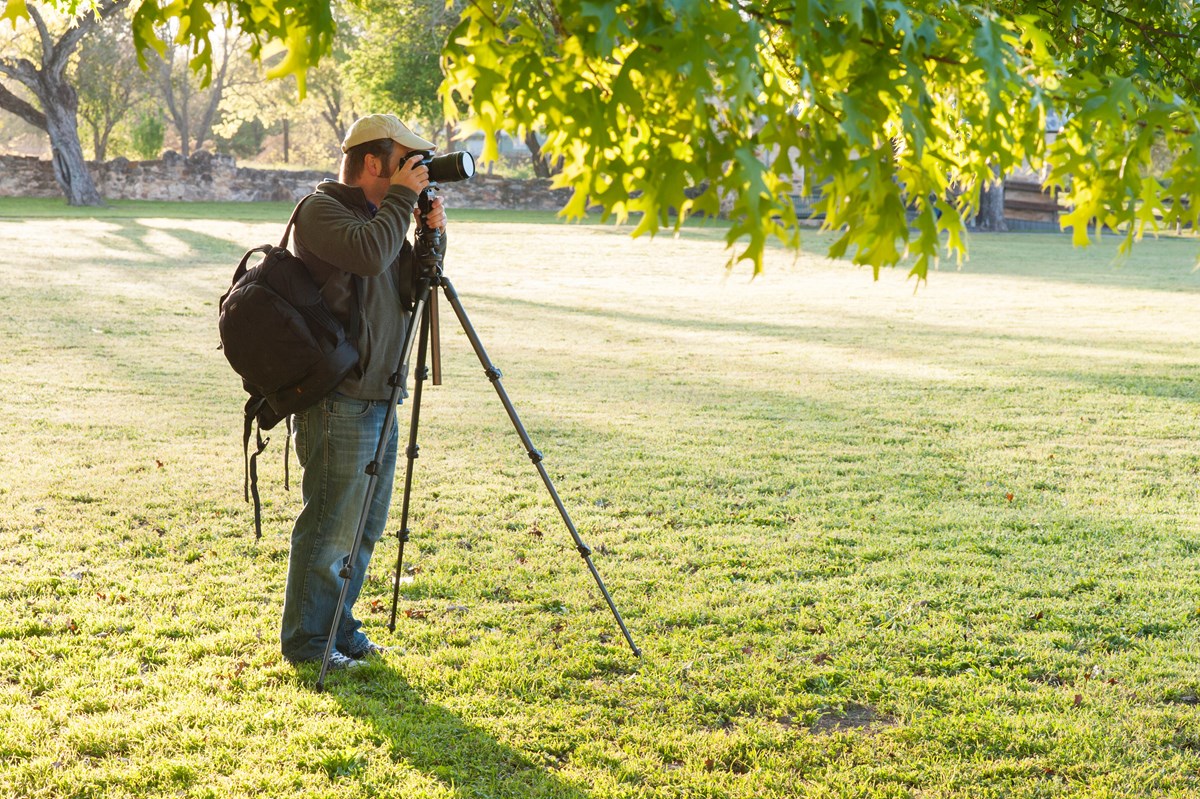Visitor uses a tall tripod and camera to take photos at the park